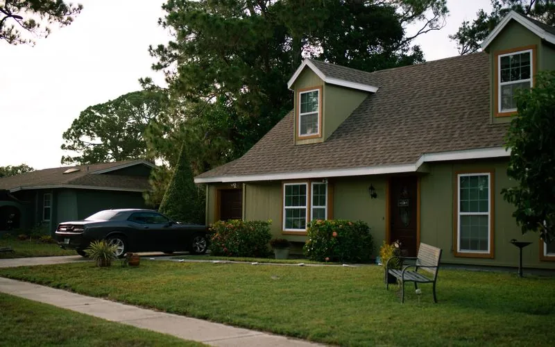 Casa con jardín y un carro estacionado en la entrada
