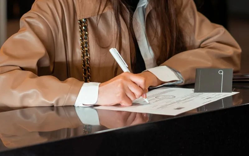 Una mujer firmando un documento en un mostrador